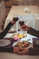 Beautiful young couple with glasses of red wine in luxury restaurant