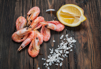 shrimp, lemon and sea salt on a dark wooden background