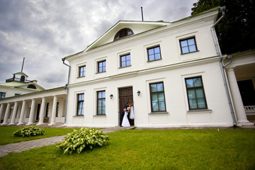 Fototapeta na wymiar Жених и невеста целуются в дверях усадьбы 