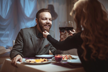 Beautiful young couple with glasses of red wine in luxury restaurant