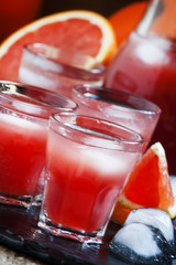 Cool juice from blood orange with ice cubes on a dark background