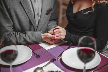 Beautiful young couple with glasses of red wine in luxury restaurant