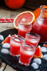 Cool juice from blood orange with ice cubes on a dark background