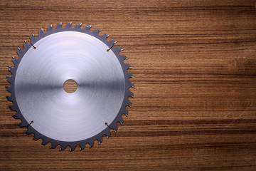 Circular saw blade on wooden background