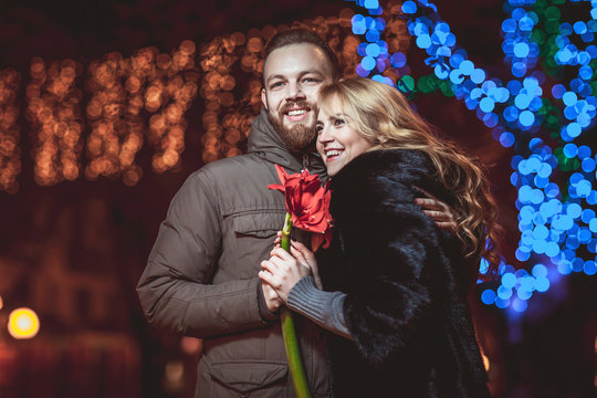 loving young couple walking outdoors in winter. Girl holding a flower