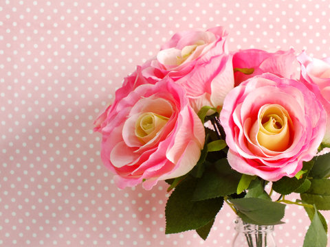 artificial rose flower close up on pink polka dot with space copy background