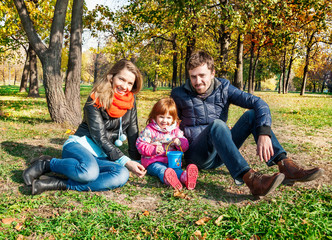 Naklejka na ściany i meble Happy young family in an autumn park