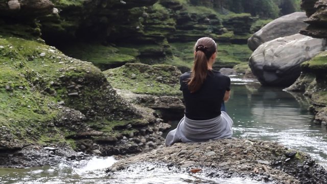 Girl sitting near a mountain river