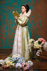 queen in royal dress reading a book. actress with an old dress