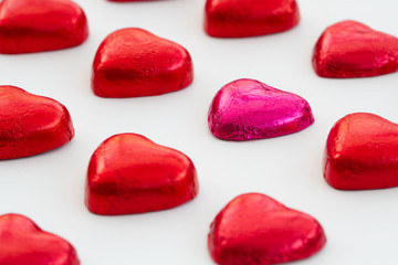 Heart shaped, Valentine chocolates on an isolated white background. Candy in rows in a grid pattern and with an odd chocolate in one row.