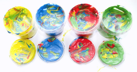 Color mixed paint in plastic jars for drawing isolated on white soiled background. Children's creativity. Finger paint. Paint cans with various colors. Background of Multi Colored Paint.