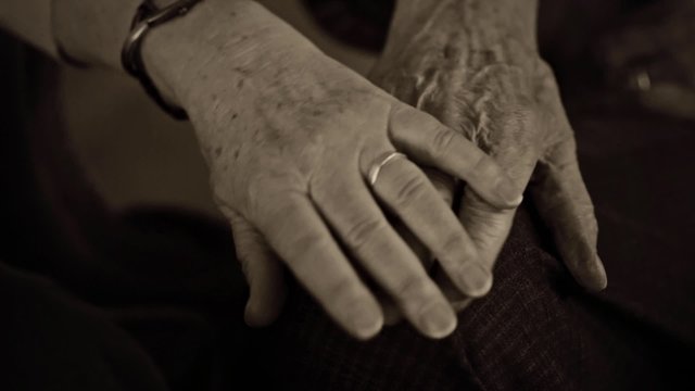 Woman caressing old mans hand