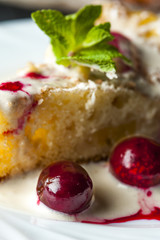 Piece of pineapple pie and cherries on white plate