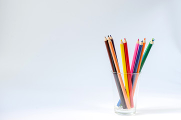 group of colored pencil in glass on white background