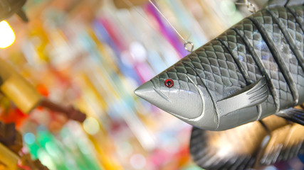 wooden fish hanging by a rope neighboring in shops on colorful b © supitstockphoto