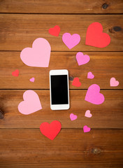 close up of smartphone and hearts on wood