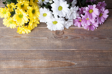 Pink, white and yellow oxeye daisy flowers bouquet on wooden background.