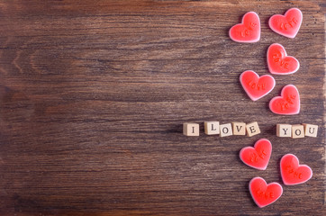 Heart shaped chewing candies and words "I love you" on cubes,  wooden background. Vintage effect. Free space for your text