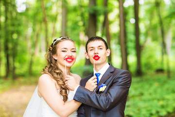 April Fools' Day. Wedding couple posing with stick lips, mask. 