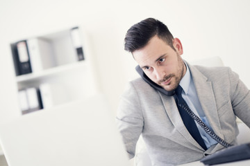 Businessman on phone while using computer in the office