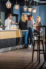 Customers With Bartender Standing At Counter