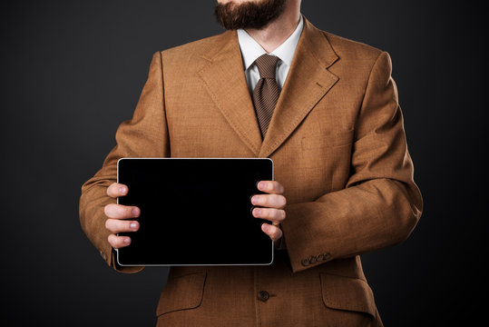 Close-up of the front view of a businessman who is browsing on his tablet