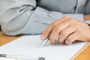 Human hand signing white paper on wood table