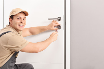 Cheerful locksmith installing a door lock