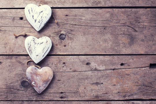 Three decorative  hearts on vintage wooden background.