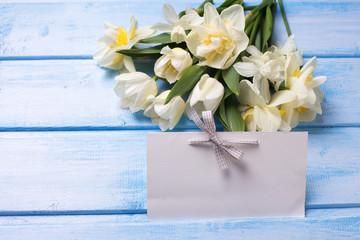 White tulips and narcissus flowers with empty tag for text on bl