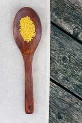 Millet on wooden spoon on a napkin on a wooden background