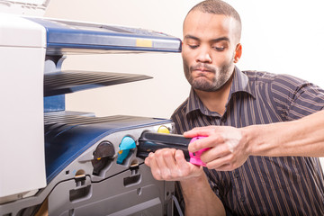 man changing magenta cartridge in color printer