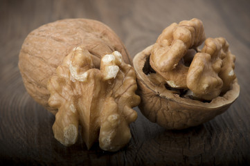 Walnut kernels and whole walnuts on rustic old wooden table