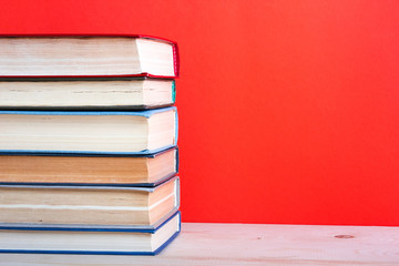 Open hardback book on wooden deck table and red background