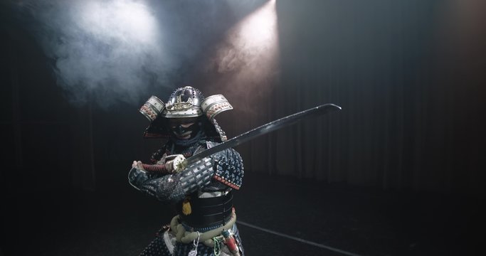 Japanese samurai in the historical suit threatens with a sword , posing for the camera, slow motion