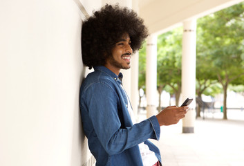 Smiling modern man standing outside with cell phone
