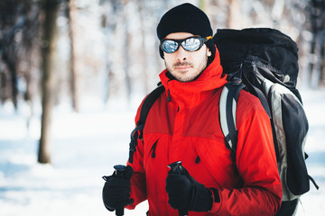 Fototapeta na wymiar Man hiking at winter mountain/Portrait of a man hiker. He is trekking in snow forest at winter mountain. Healthy lifestyle winter adventure