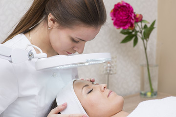 Woman and cosmetician during facial spa procedure in the beauty