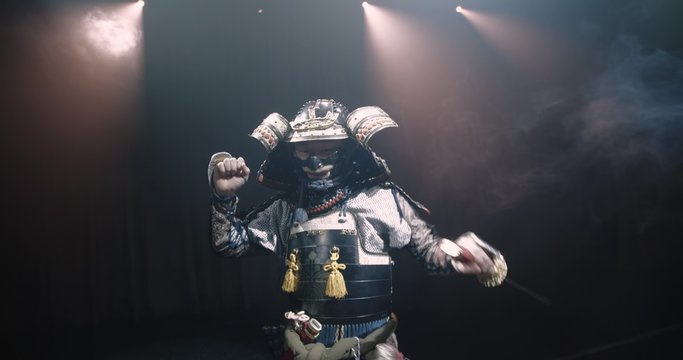 Japanese samurai in the historical suit threatens with a sword , posing for the camera, slow motion