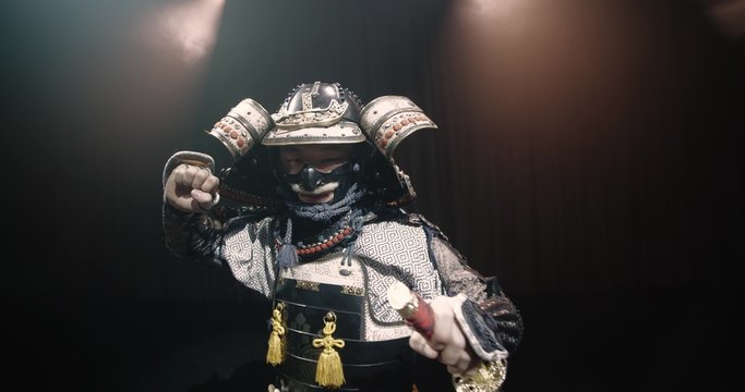 Japanese samurai in the historical suit threatens with a sword , posing for the camera, slow motion