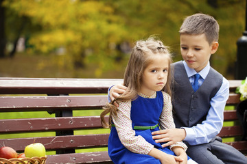 Sad little girl is sitting on the bench, outdoor shoot