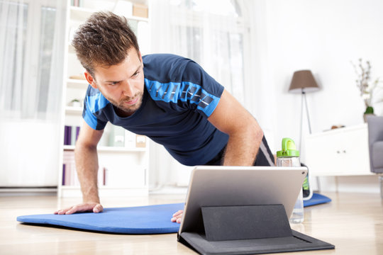 Man Doing Planking While Watching Movie on Tablet