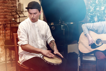 stylish percussionist playing on leather drum on a concert, hand