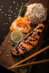 Teriyaki salmon with rice on a wooden platter. Top view.