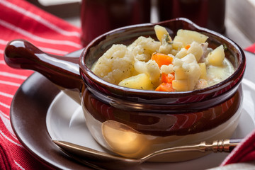 Homemade cauliflower soup in a brown bowl.