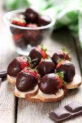 Fresh strawberries dipped in dark chocolate on grey wooden backg