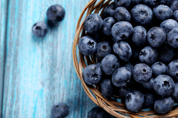 Tasty blueberries in basket on a blue wooden table