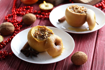 Baked apples on plate on red wooden table