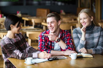 guy and two girls having fun at the cafe. The boy and two girls sitting in a cafe. Guy and two girls communicate in cafe