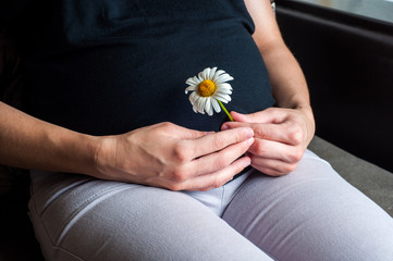 Hand of the pregnant asian women touch her belly while sitting in the home